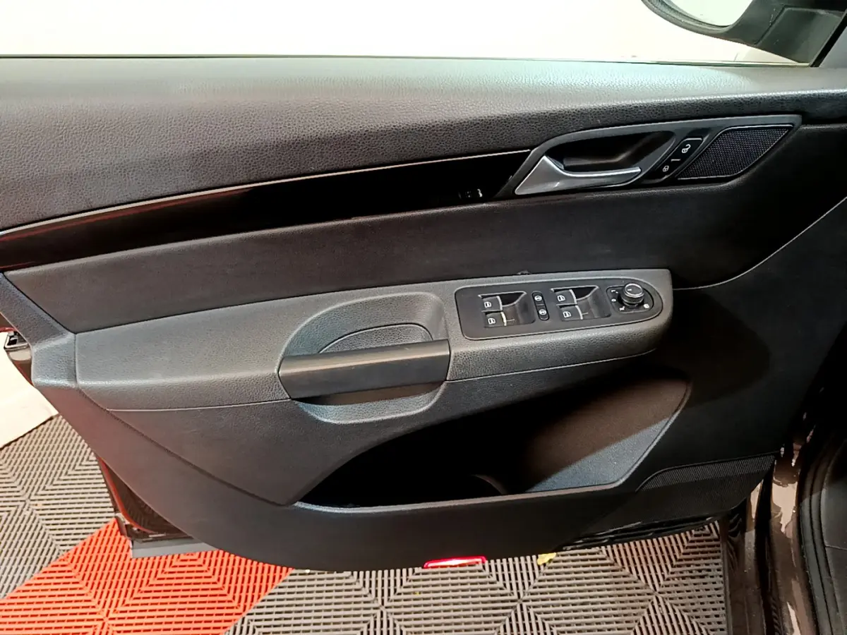 Vue rapprochée de la porte avant gauche noire du Volkswagen Sharan 2017 avec commandes électriques et poignée intégrée.