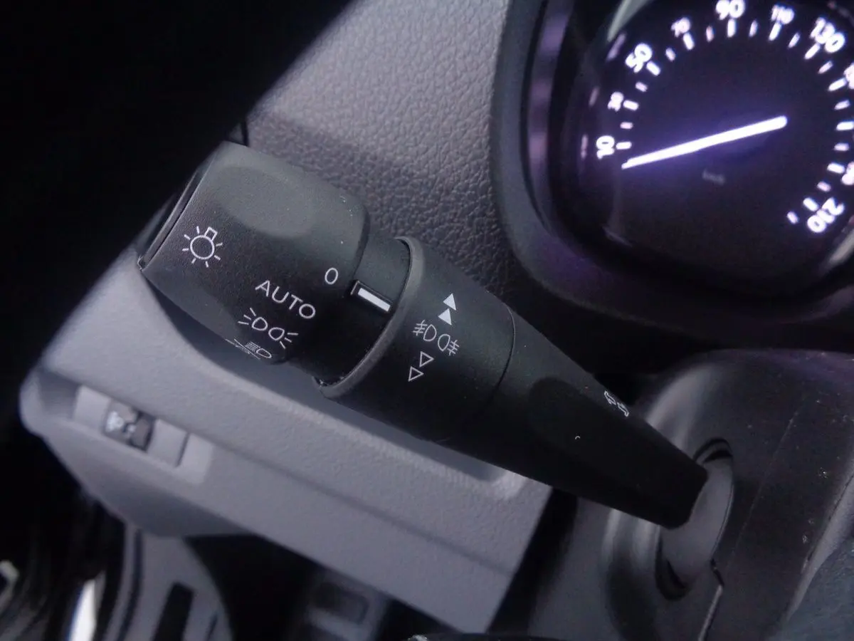 Gros plan sur la manette des phares et clignotants du Peugeot Expert Fourgon noir, tableau de bord partiellement visible.