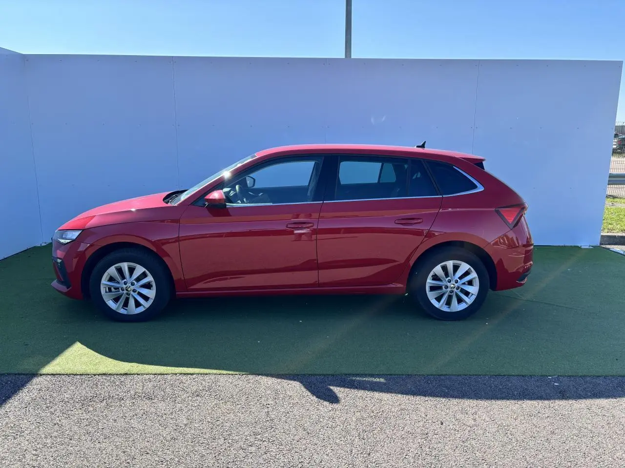 Profil côté gauche d'une Skoda Scala 2024 rouge Velvet Metal avec jantes alliage 16 pouces sur fond neutre.