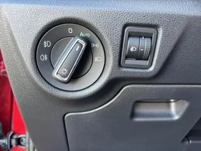 Gros plan sur le bouton de commande des phares et réglage de luminosité dans une Skoda Scala rouge Velvet Metal 2024.