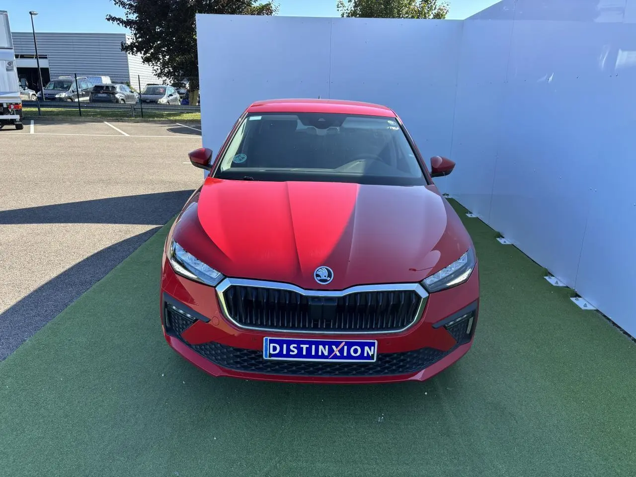 Vue frontale d'une Skoda Scala 2024 rouge velvet metal avec calandre noire et phares LED allumés.