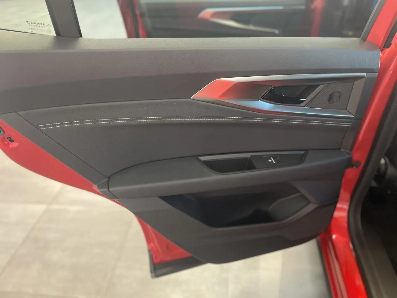 Intérieur côté gauche de la porte avant rouge du Renault Rafale 2025, avec garniture noire et surpiqûres blanches.