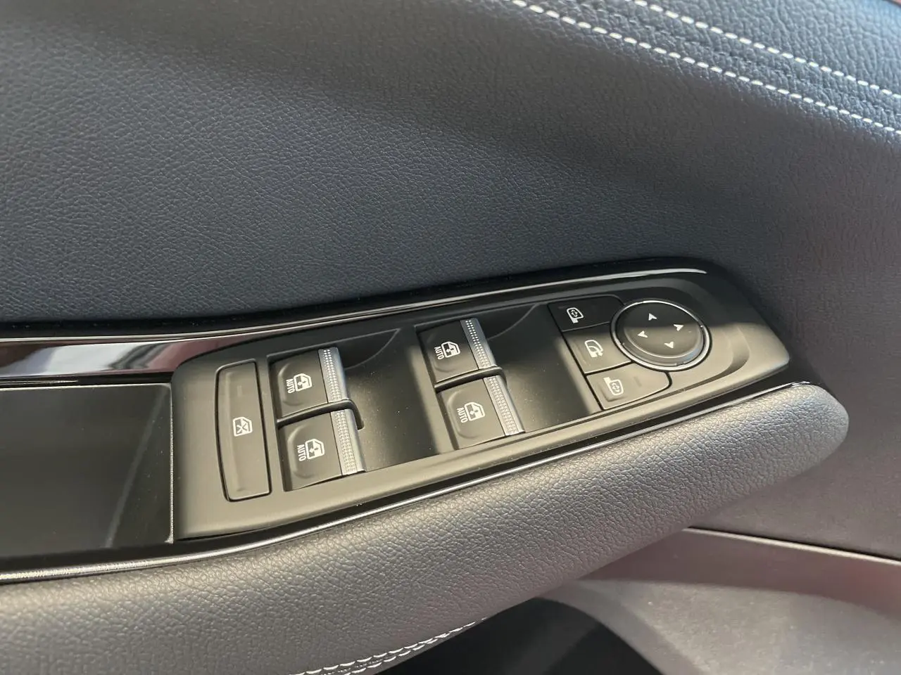 Gros plan sur les commandes de lève-vitres et rétroviseurs côté conducteur d'une Renault Rafale 2025 noire.