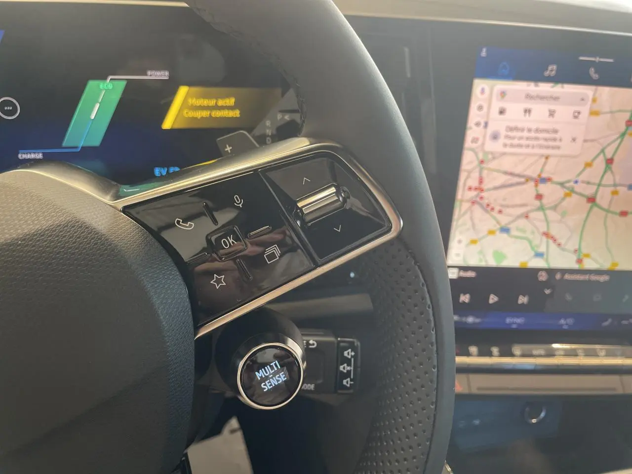 Gros plan sur le volant et le tableau de bord numérique du Renault Rafale 2025, avec écran tactile affichant une carte.