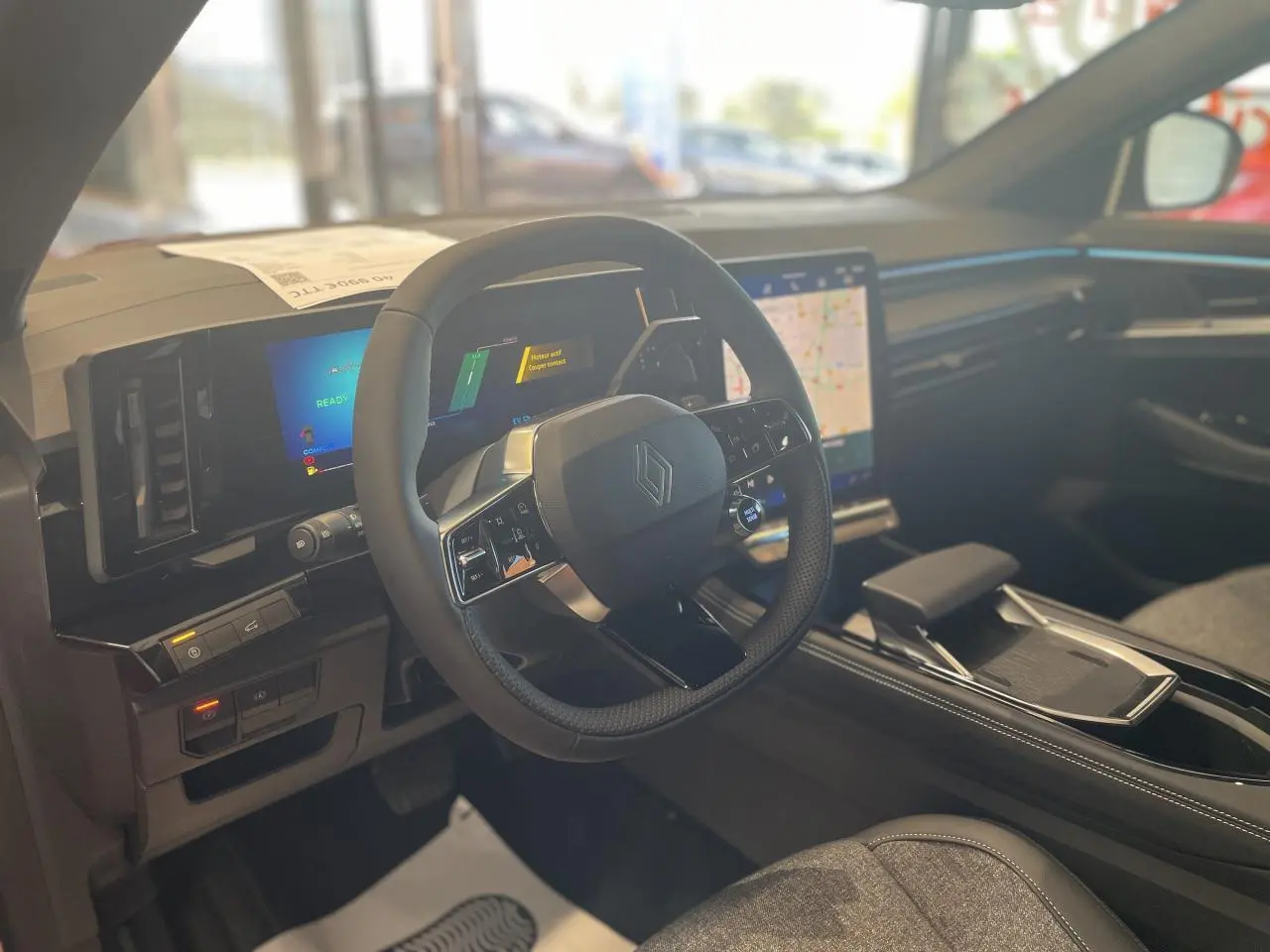 Intérieur du Renault Rafale 2025 vu côté conducteur, volant multifonction et écran tactile central lumineux.