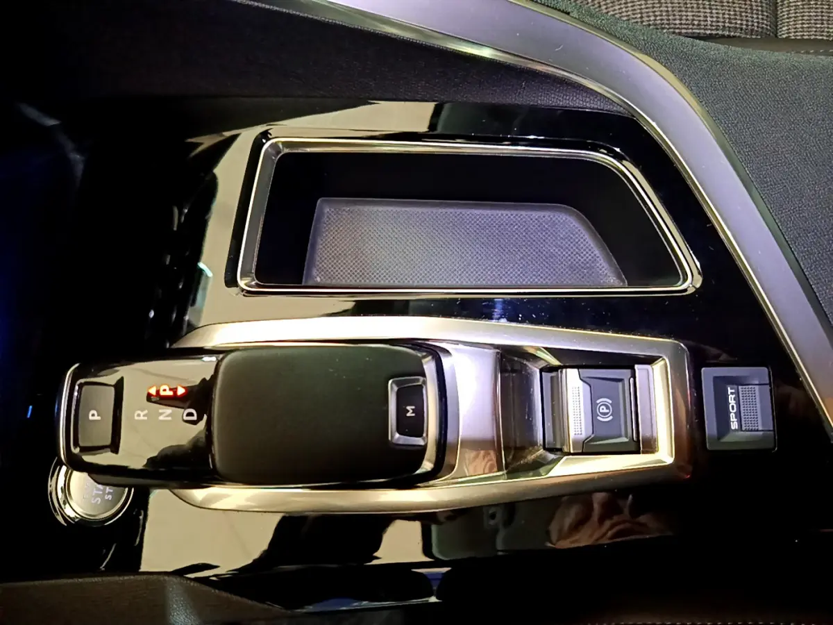 Vue rapprochée de la console centrale noire brillante du Peugeot 3008 gris clair avec levier de vitesse automatique et bouton Sport.