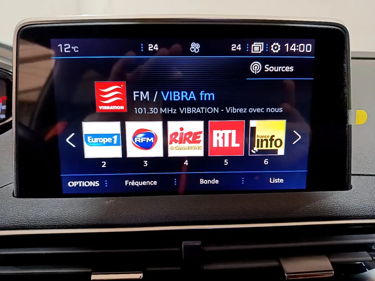 Écran tactile central du tableau de bord du Peugeot 3008 gris clair affichant les radios FM avec logos colorés.
