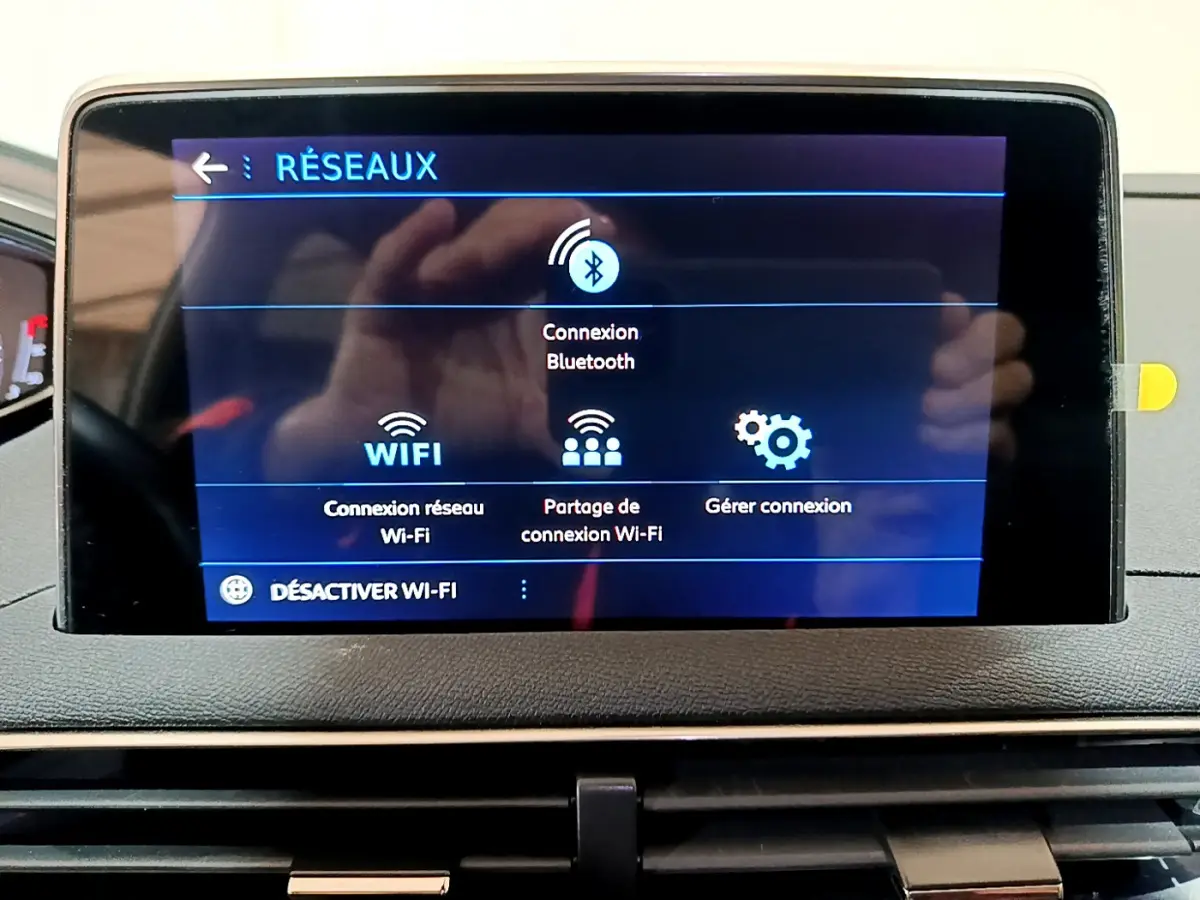 Écran tactile central affichant les options réseau Bluetooth et Wi-Fi dans le tableau de bord du Peugeot 3008 gris clair.