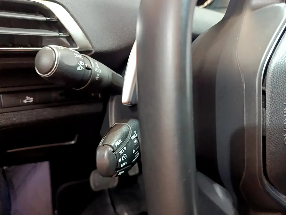 Gros plan sur les commandes au volant noir du Peugeot 3008 gris clair, côté gauche du tableau de bord.