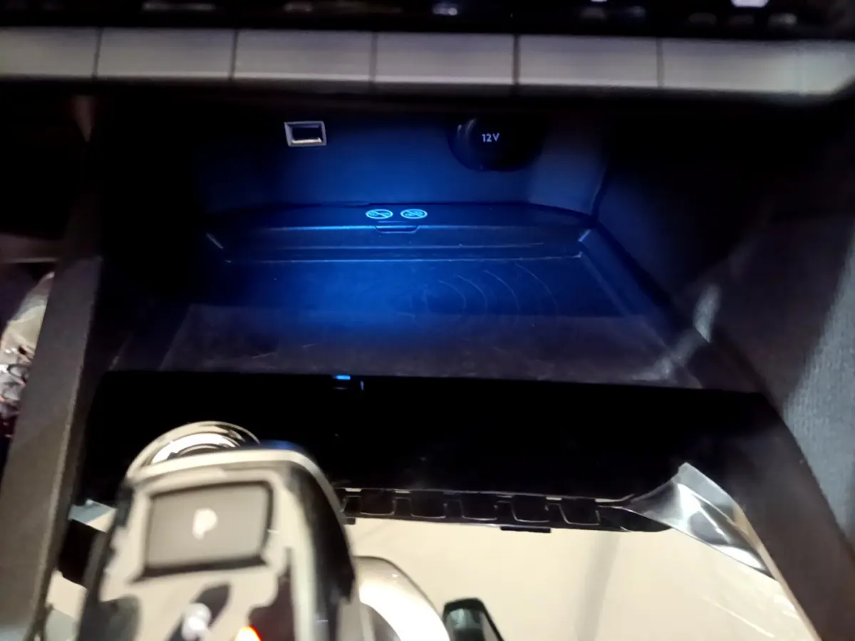 Gros plan sur la console centrale noire du Peugeot 3008 gris clair, avec prise 12V et port USB visibles.