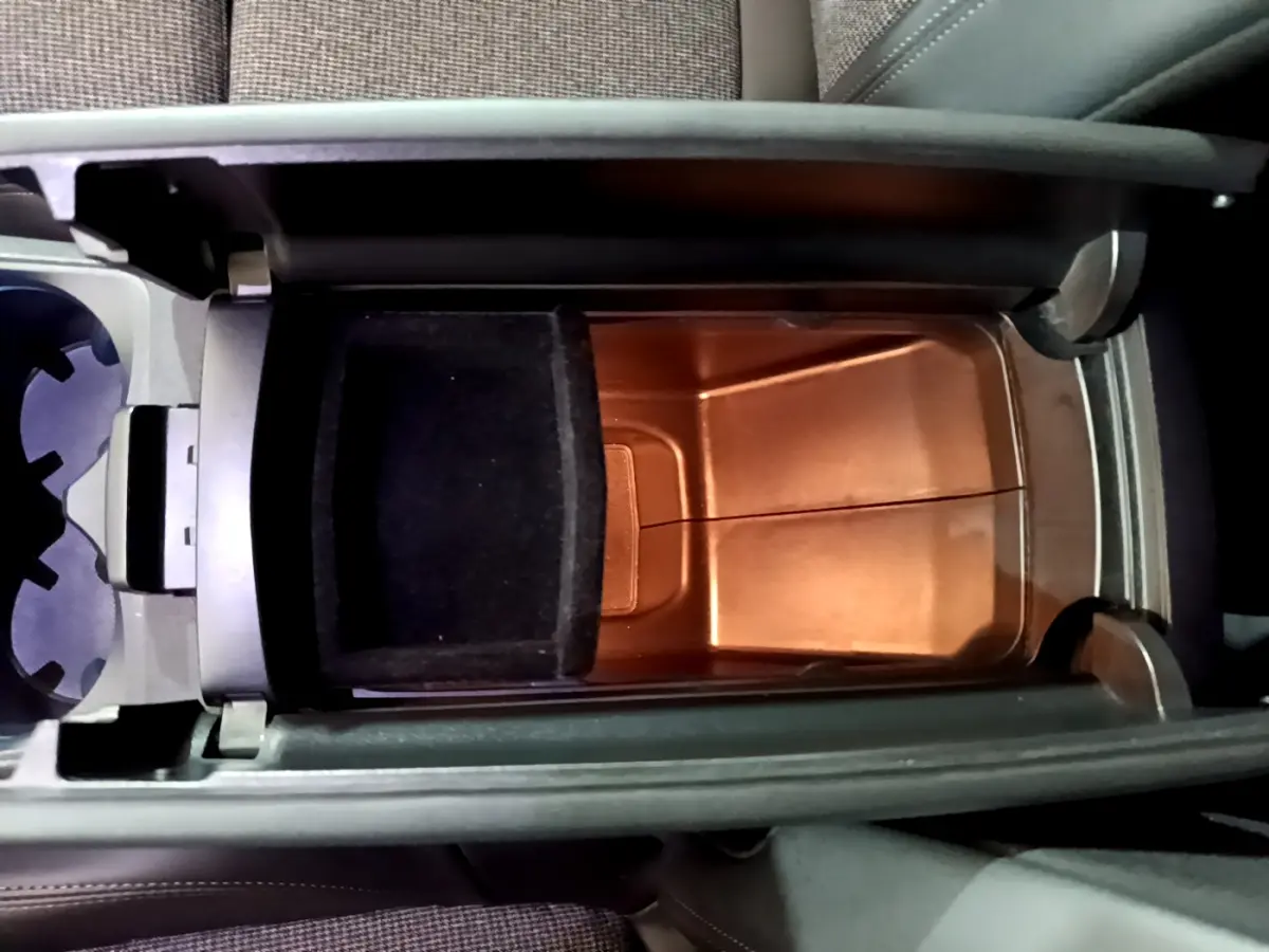 Vue plongeante sur le rangement central intérieur du Peugeot 3008 gris clair, avec compartiment ouvert et porte-gobelets à côté.