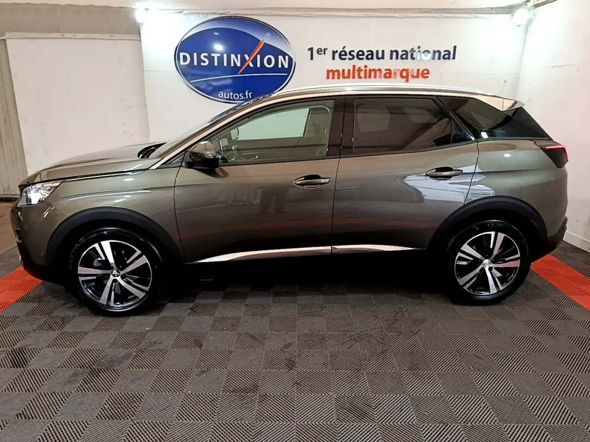 Profil côté gauche du Peugeot 3008 gris clair 2020 avec jantes alliage et toit noir contrasté dans un showroom.