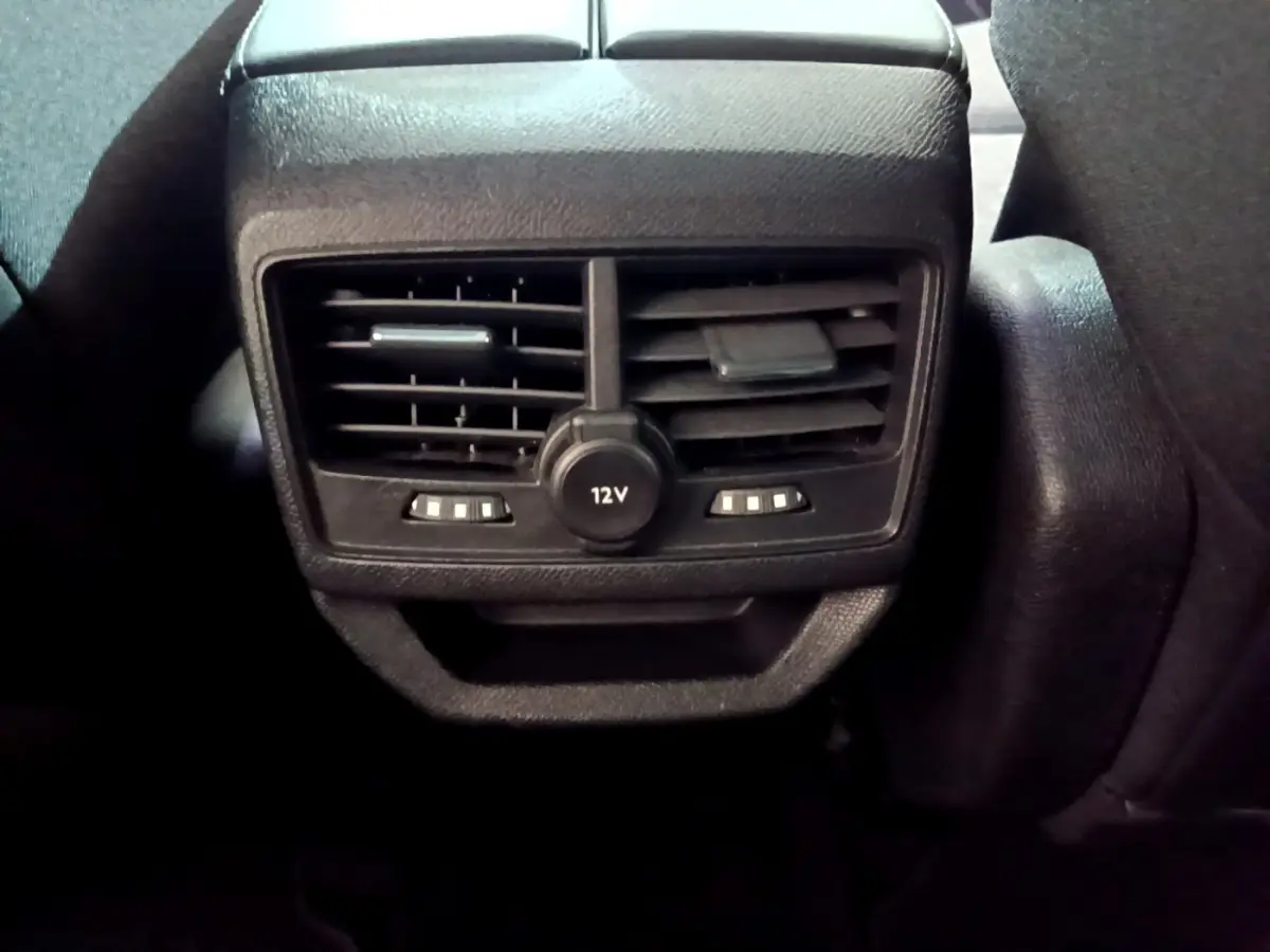Gros plan sur la console arrière noire du Peugeot 3008 gris clair 2020, avec prises d'air et prise 12V visible.