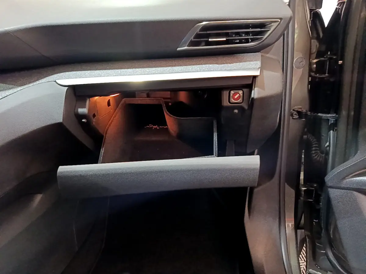 Intérieur du Peugeot 3008 gris clair, vue sur la boîte à gants ouverte côté passager avec éclairage intérieur.