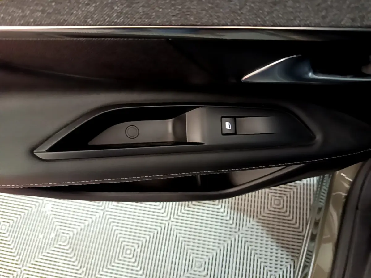 Détail de la commande de lève-vitre côté conducteur sur la porte intérieure noire du Peugeot 3008 gris clair 2020.