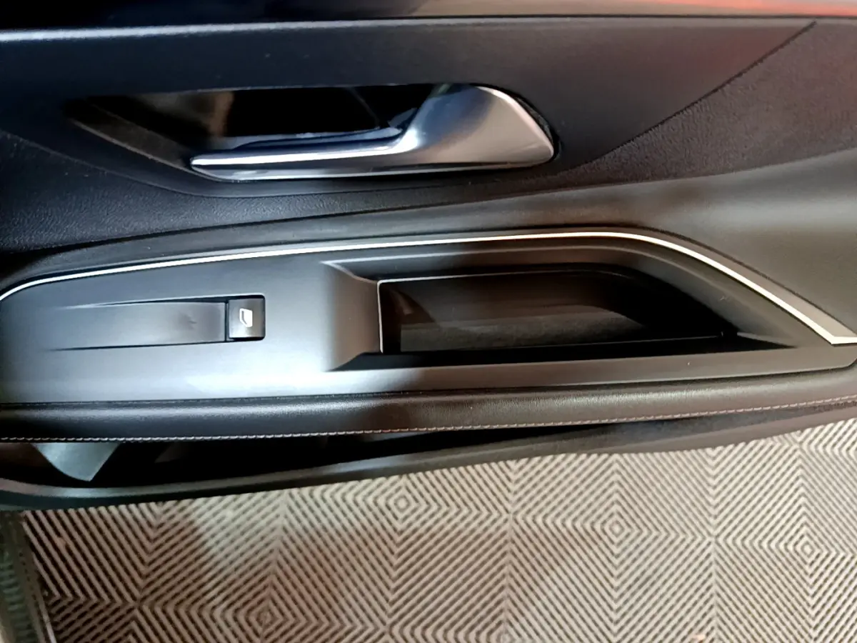 Poignée intérieure et commande de lève-vitre côté conducteur du Peugeot 3008 gris clair, finition Allure Business.