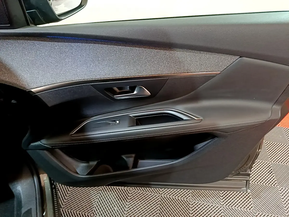 Vue rapprochée de la porte côté gauche du Peugeot 3008 gris clair, avec poignée et garniture noire élégante.