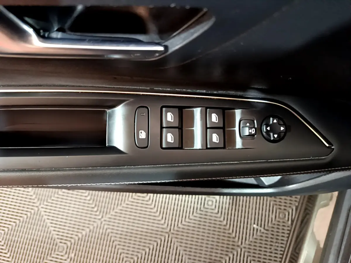 Panneau de commande des vitres et rétroviseurs côté gauche en cuir noir dans un Peugeot 3008 gris clair 2020.