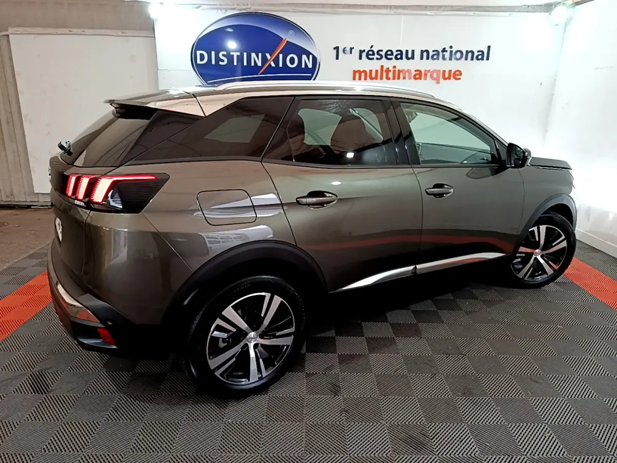 Vue 3/4 arrière droite d'un Peugeot 3008 gris clair avec feux arrière LED et jantes alliage noires et argentées.
