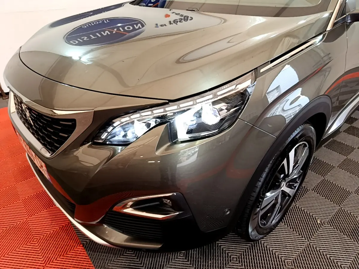 Vue 3/4 avant droit d'un Peugeot 3008 gris clair avec phares LED allumés et jantes alliage noires.