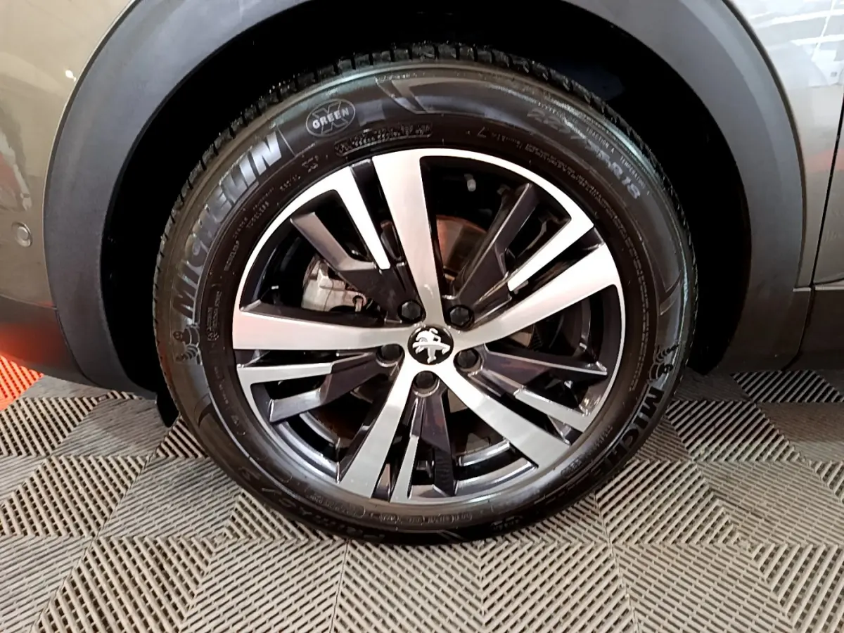 Gros plan sur la roue avant droite gris clair du Peugeot 3008 avec jante alliage et pneu Michelin visible.