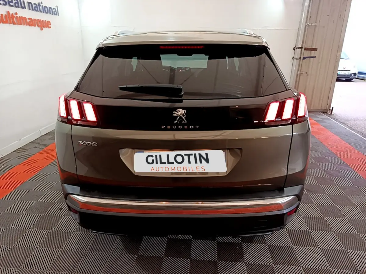 Vue arrière d'un Peugeot 3008 gris clair avec feux arrière LED caractéristiques et logo lion central.
