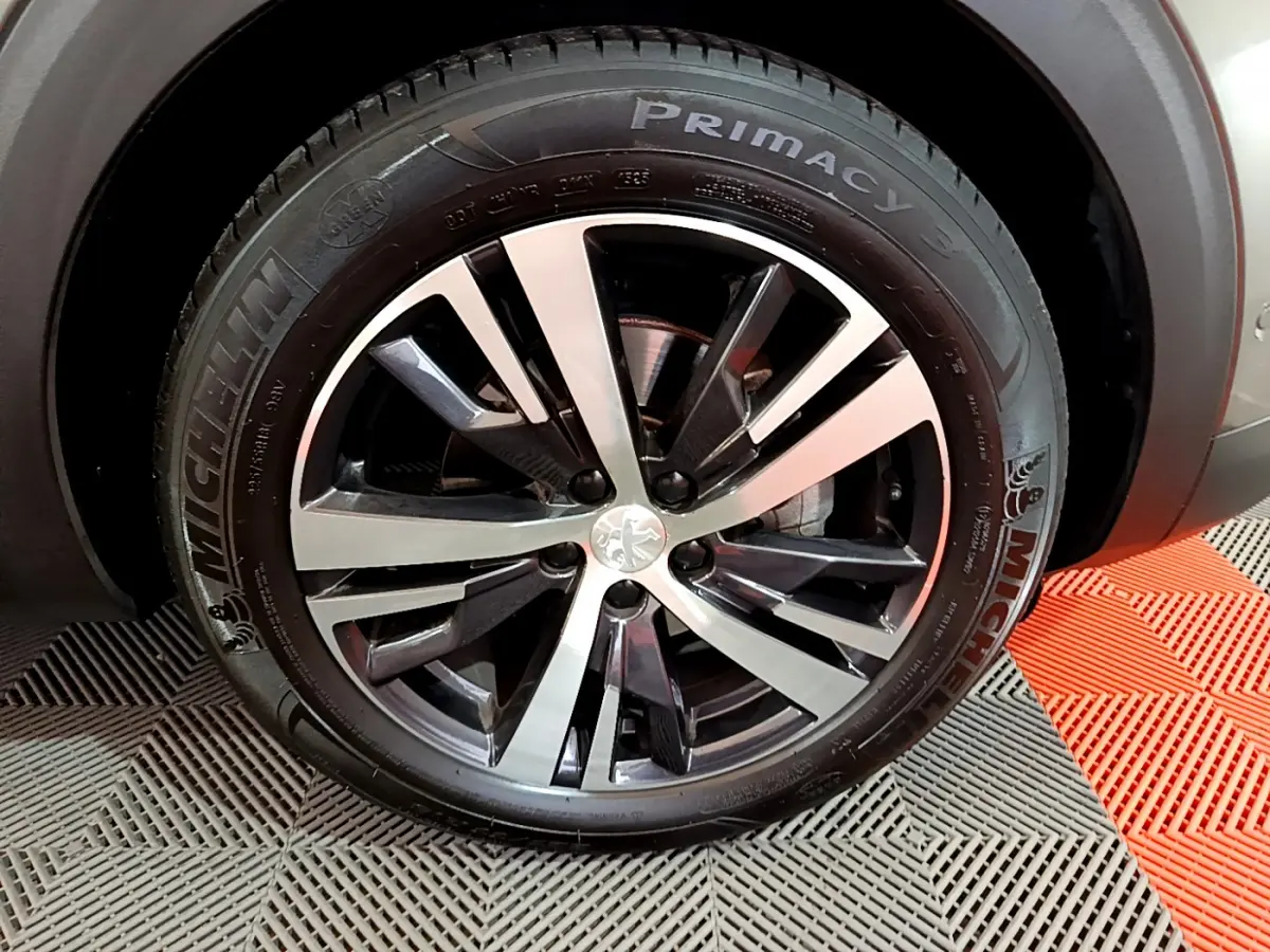Gros plan sur la jante alliage bicolore et pneu Michelin d'un Peugeot 3008 gris clair, côté avant droit.