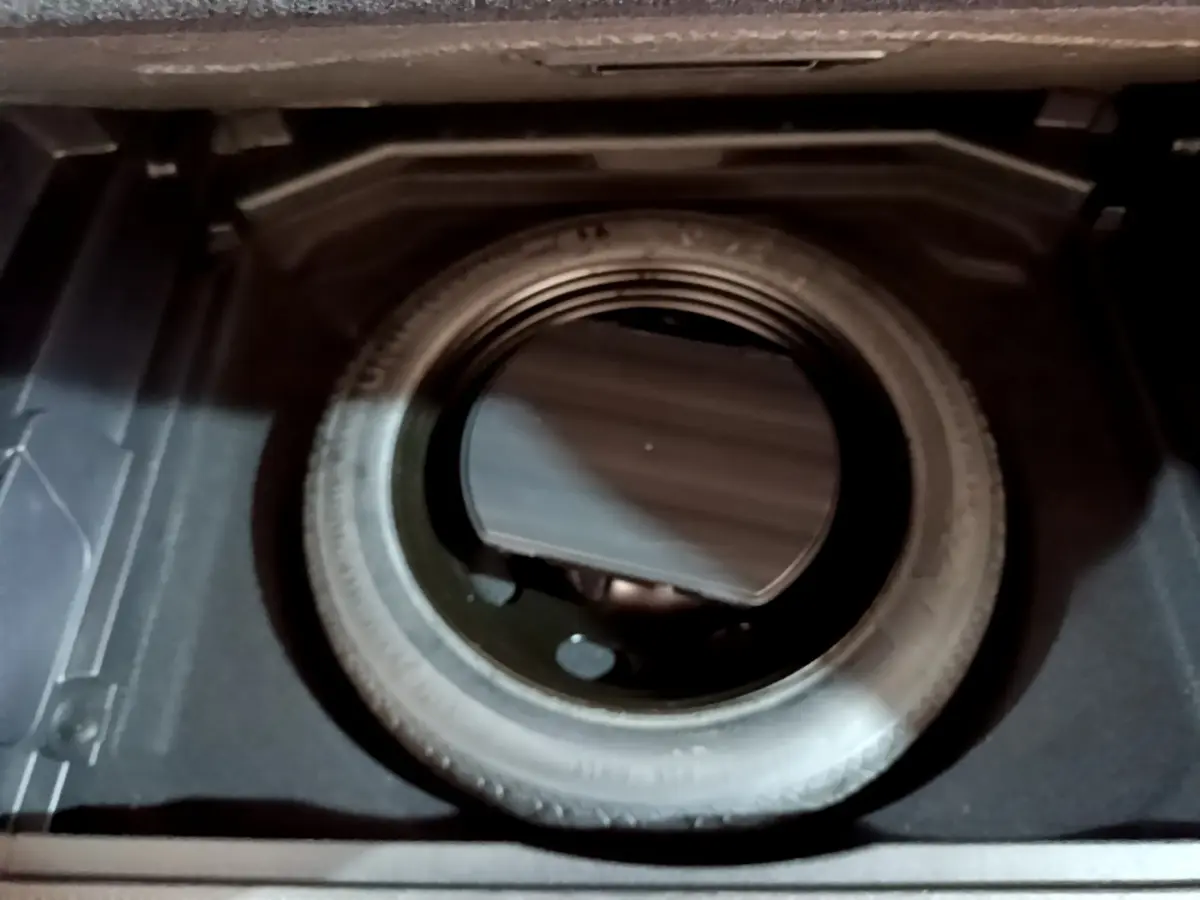 Vue plongeante sur la roue de secours noire dans le coffre du Peugeot 3008 gris clair 2020.