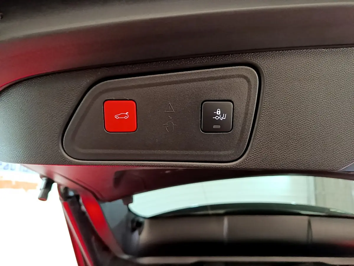 Gros plan sur les boutons de fermeture électrique du coffre et de rabattement des sièges dans un Peugeot 3008 gris clair.