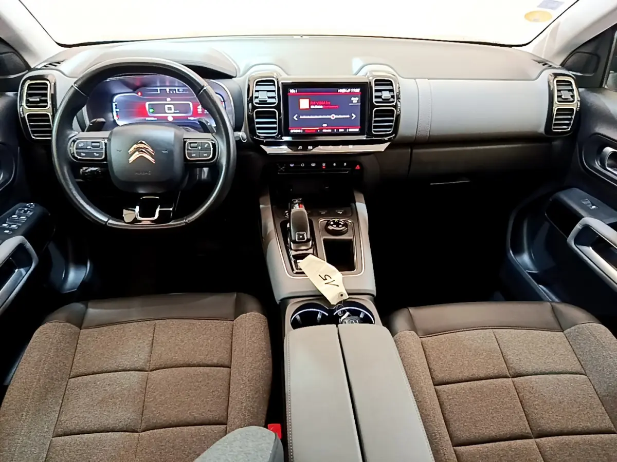 Intérieur du Citroën C5 Aircross 2020 vu de face, volant cuir noir et écran tactile central lumineux rouge.
