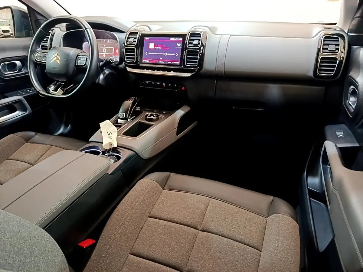 Intérieur du Citroën C5 Aircross 2020, vue côté conducteur, tableau de bord moderne avec écran tactile et volant cuir noir.