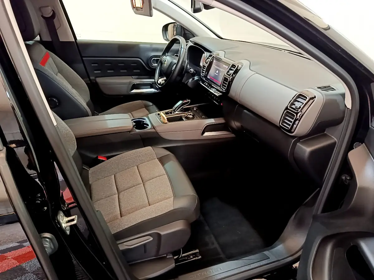 Intérieur côté conducteur du Citroën C5 Aircross noir 2020, sièges gris et tableau de bord moderne avec écran tactile.