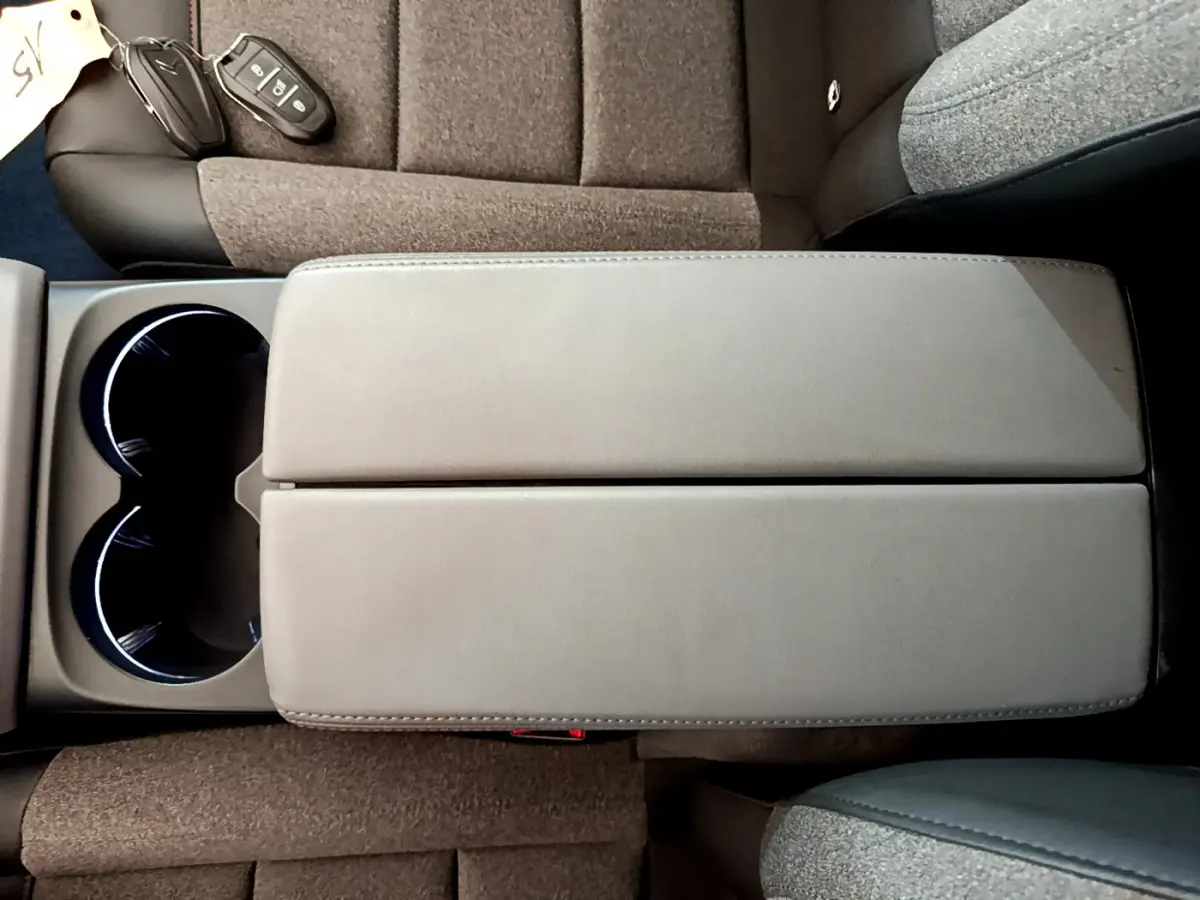 Vue plongeante sur l'accoudoir central gris et les sièges tissu marron du Citroën C5 Aircross 2020 noir.