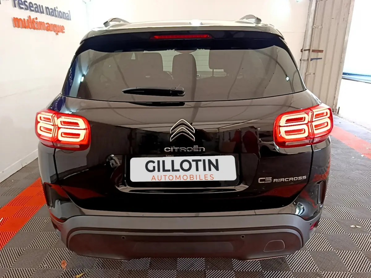 Vue arrière du Citroën C5 Aircross noir avec feux arrière LED distinctifs allumés en intérieur showroom.