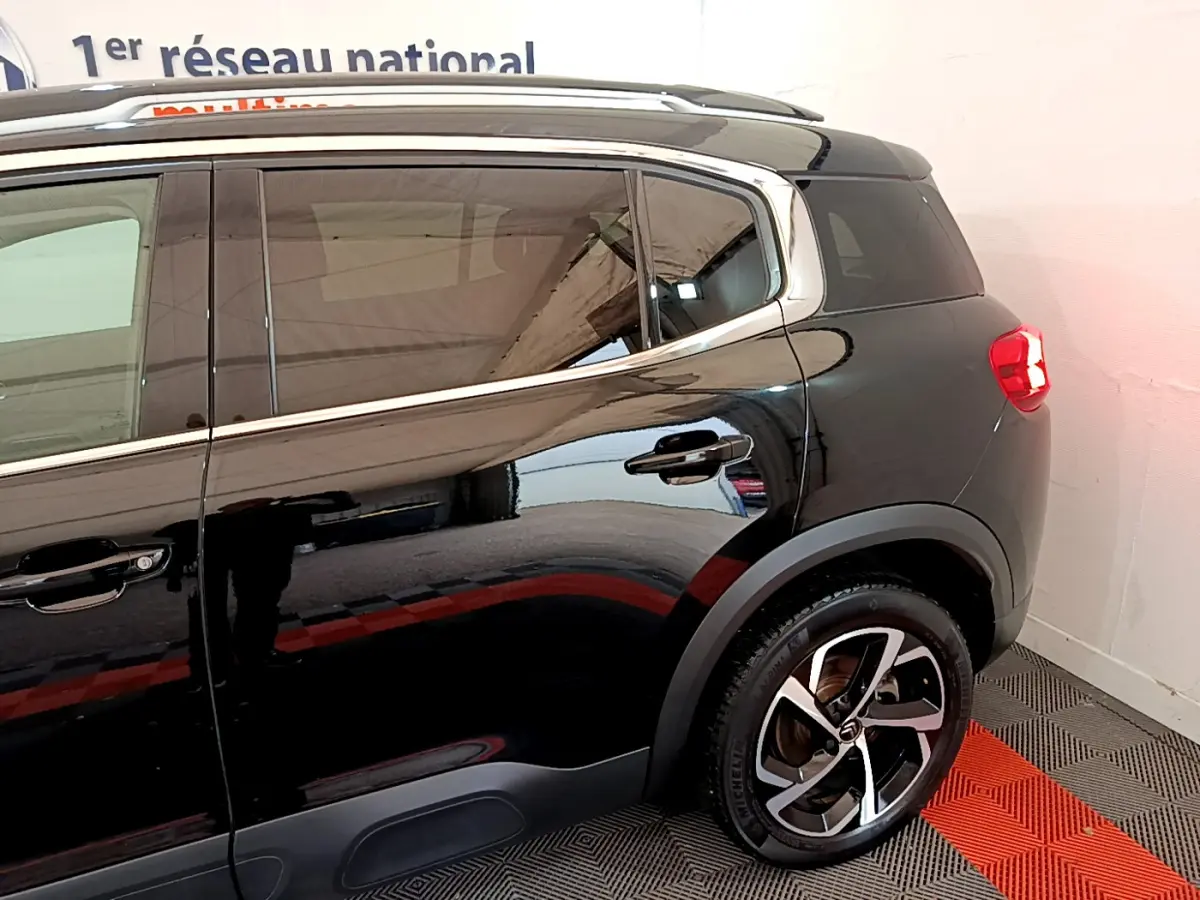 Vue latérale arrière droite du Citroën C5 Aircross noir, mettant en valeur les jantes alliage et les contours chromés des vitres.