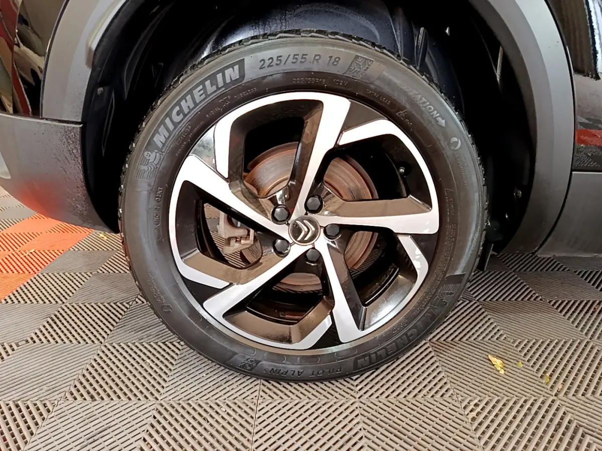Gros plan sur la roue avant droite d’un Citroën C5 Aircross noir avec jante alliage bicolore et pneu Michelin.