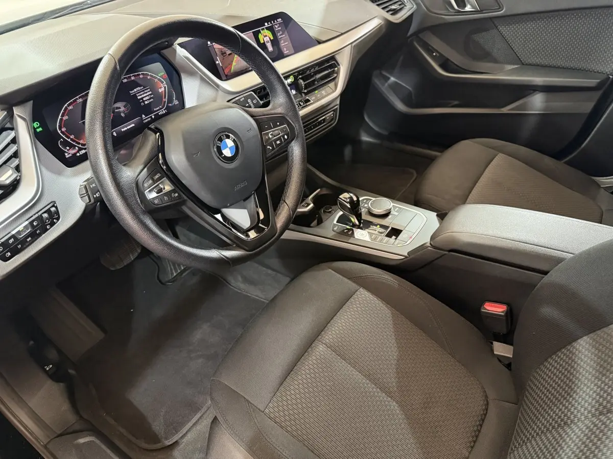 Vue intérieure côté conducteur de la BMW Série 1 116d Business Design 2022 avec tableau de bord digital et volant cuir noir.