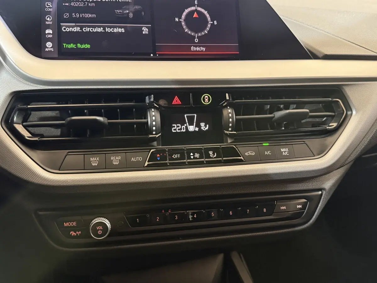 Vue rapprochée du tableau de bord central de la BMW Série 1 116d noir, avec écran tactile et commandes climatisation.