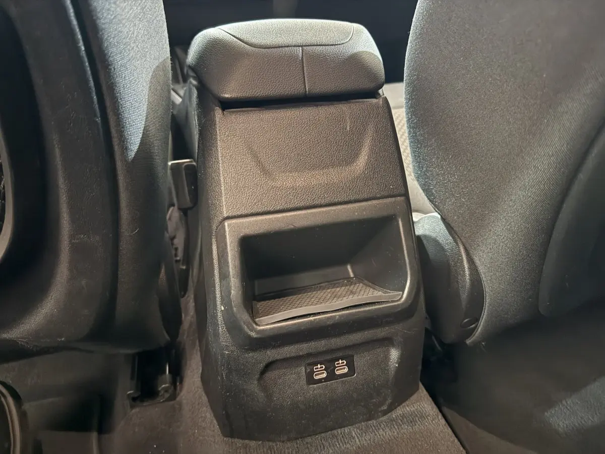 Gros plan sur la console centrale arrière noire avec ports USB, entre les sièges arrière gris foncé d'une BMW Série 1 116d.
