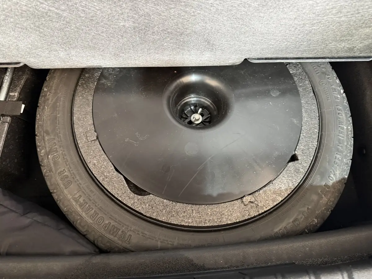 Vue rapprochée du pneu de secours noir dans le coffre d'une BMW Série 1 116d Business Design 2022.