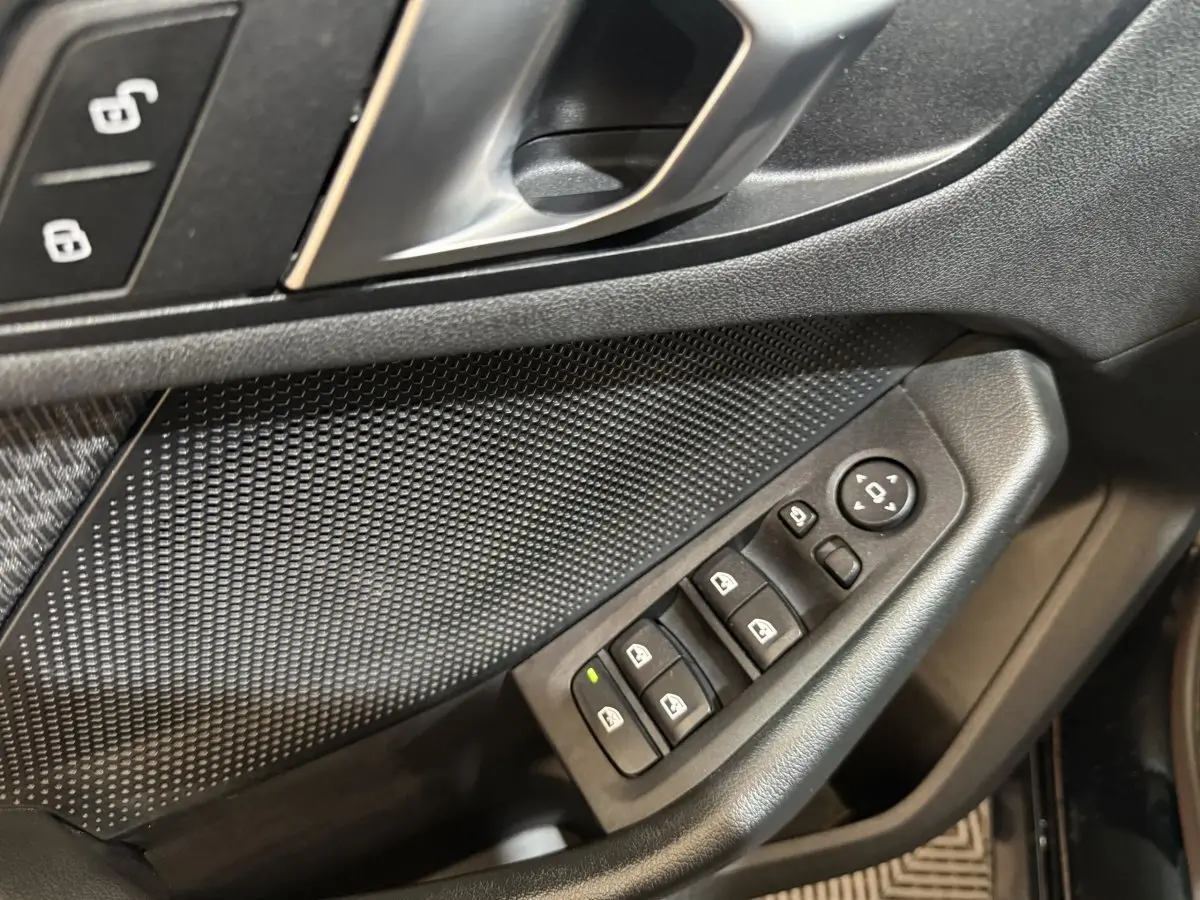 Gros plan sur la porte côté conducteur de la BMW Série 1 noire, avec commandes électriques des vitres et rétroviseurs.
