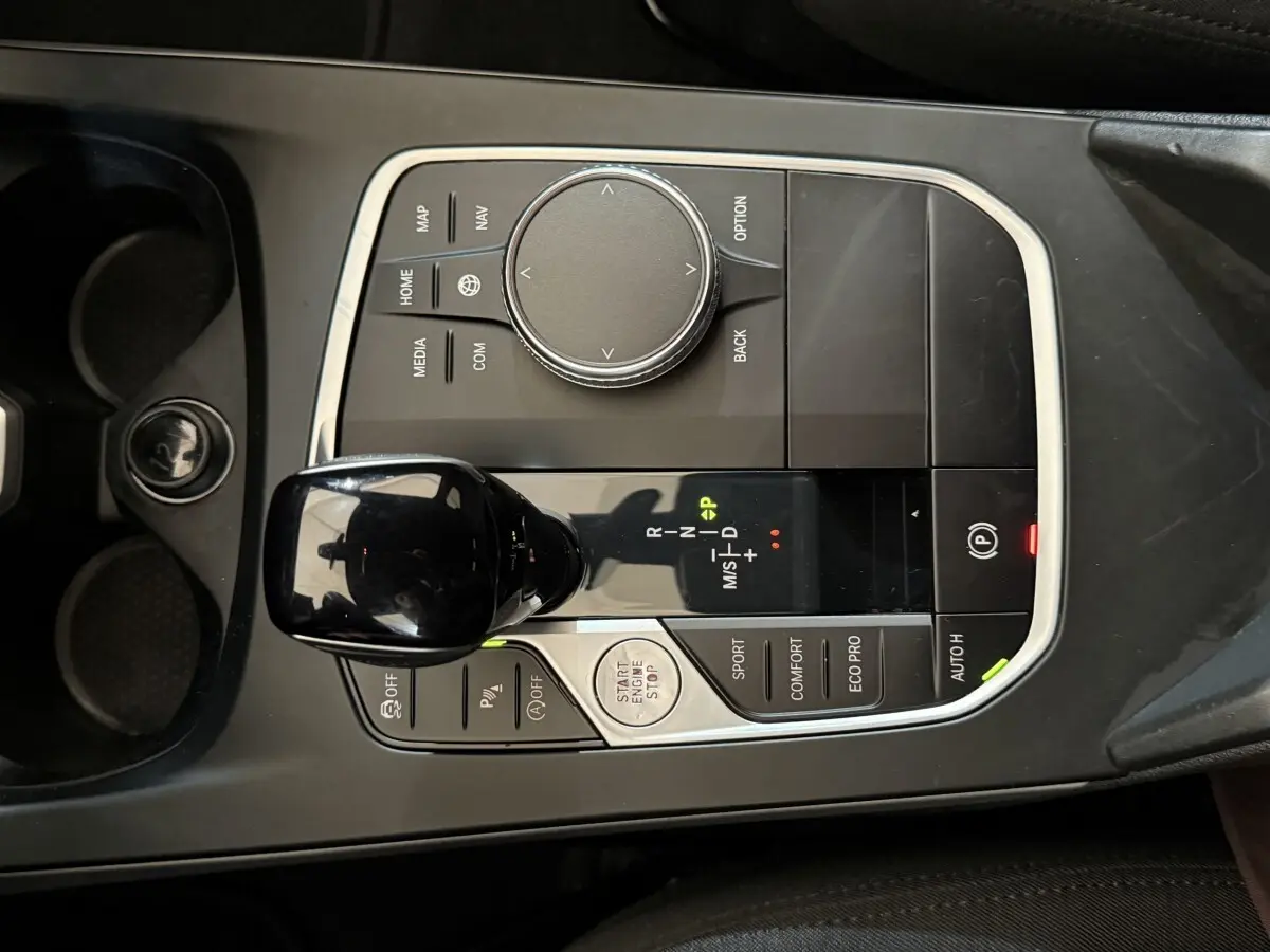 Vue plongeante sur la console centrale noire de la BMW Série 1 116d avec levier de vitesses automatique et commandes de mode de conduite.
