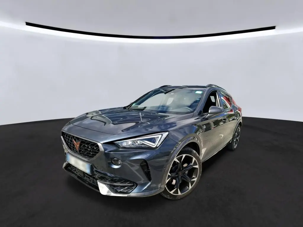 Vue 3/4 avant droite d'un CUPRA Formentor gris clair avec jantes noires et calandre distinctive en losange.