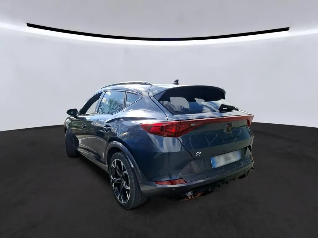 Vue 3/4 arrière droite d'une CUPRA Formentor gris clair 2024 avec feux arrière LED et jantes sport noires.