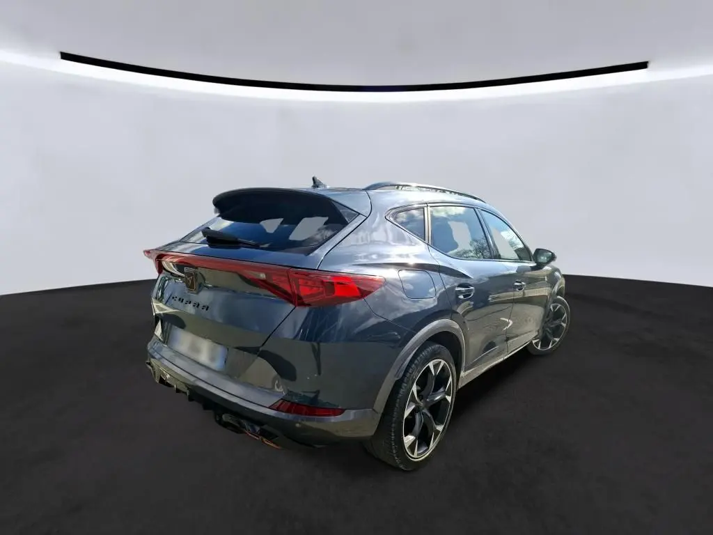 Vue 3/4 arrière droite d’un CUPRA Formentor gris clair 2024 avec jantes noires et feux arrière LED distinctifs.
