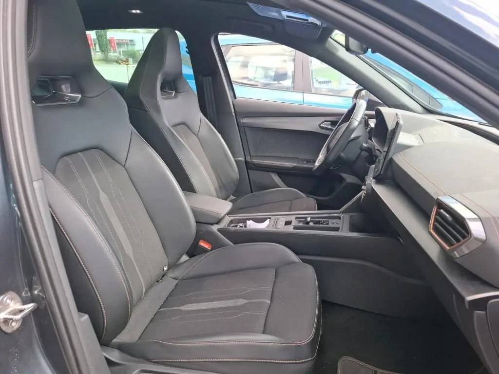 Vue intérieure côté gauche de la CUPRA Formentor 1.4 E-HYBRID 245 VZ 2024, sièges noirs en tissu avec surpiqûres contrastées.
