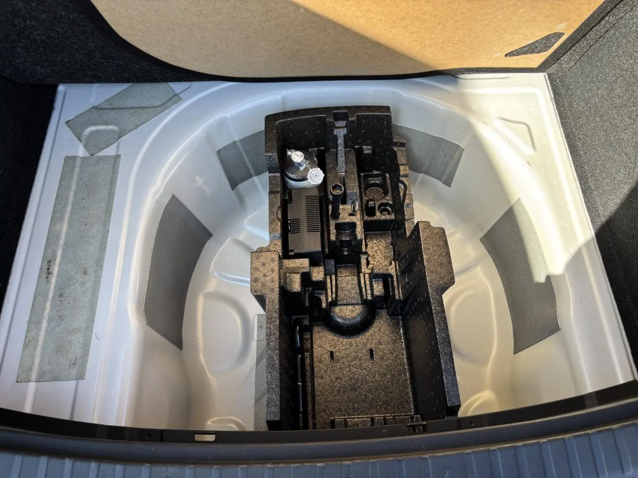 Coffre ouvert d'une Skoda Scala blanc glacier montrant le rangement pour roue de secours et outils intégrés.