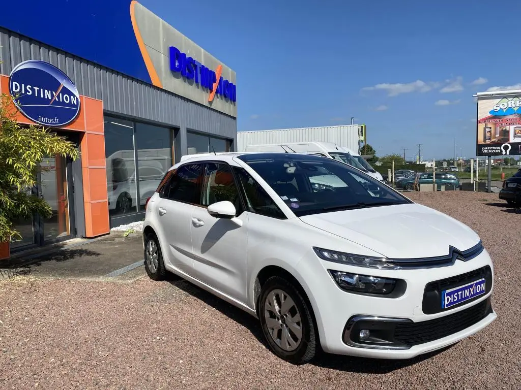 Citroën C4 Spacetourer blanc vue 3/4 avant droit, stationnée devant un concessionnaire Distinxion par temps ensoleillé.