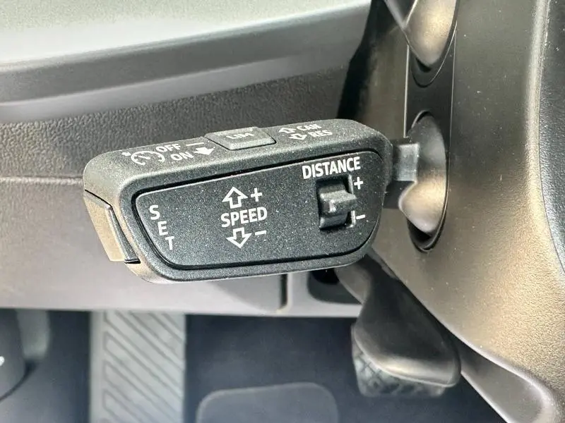 Gros plan sur la commande de régulateur de vitesse adaptatif noire dans l'habitacle d'une Audi A3 Sportback blanche Arkona 2024.