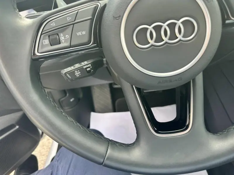 Gros plan sur le volant cuir multifonction de l'Audi A3 Sportback 2024, mettant en valeur les commandes intégrées.